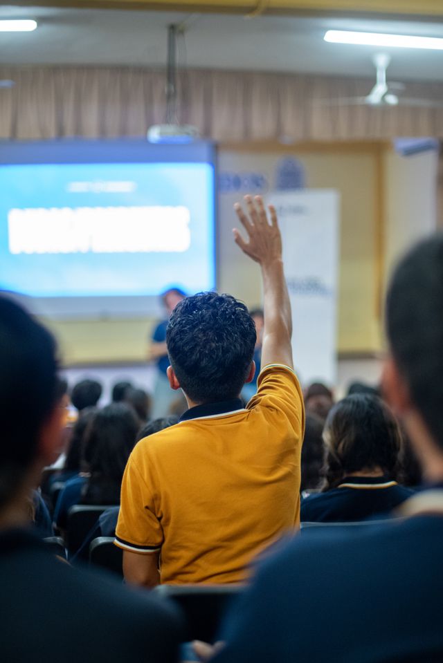 A student raising a hand during a school assembly